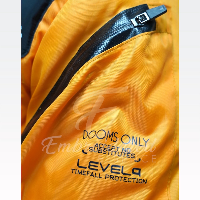 May include: Close-up of a bright orange jacket with black accents and a zipper. The jacket features the text "DOOMS ONLY ACCEPT NO SUBSTITUTES LEVEL 4 TIMEFALL PROTECTION".