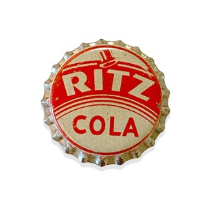 May include: A silver bottle cap with a red and white logo that says "RITZ COLA".
