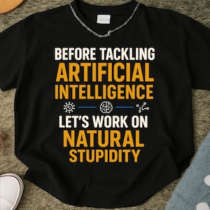 Puede incluir: Camiseta negra con el texto "BEFORE TACKLING ARTIFICIAL INTELLIGENCE LET'S WORK ON NATURAL STUPIDITY" en blanco y amarillo. La camiseta tiene un collar de cadena plateada.