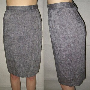 Puede incluir: Una falda lápiz gris con un sutil patrón texturizado. La falda es de largo hasta la rodilla y tiene una silueta recta.