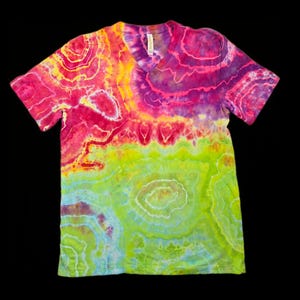 May include: A vibrant, tie-dye V-neck t-shirt. The shirt features a blend of colors, including pink, yellow, green, and purple, creating a unique, abstract pattern. The design resembles layered, organic shapes. The shirt is displayed against a black background.