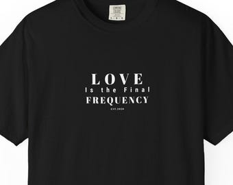 Puede incluir: Una camiseta negra de manga corta con texto blanco centrado en el pecho que dice LOVE IS THE FINAL FREQUENCY EST.2024. La camiseta tiene cuello redondo y un corte estándar, con una pequeña etiqueta blanca visible en la zona del cuello.