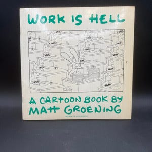 May include: A vintage paperback book titled "WORK IS HELL" in green lettering. The cover features a black and white cartoon illustration of office workers. The author's name, Matt Groening, is also displayed.