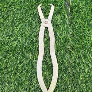 May include: A vintage silver-colored spanner plier tool with curved handles and pointed tips. The tool is labeled with text including "No. 420 Spanner Pliers" and other markings. The tool is set against a green artificial grass background.