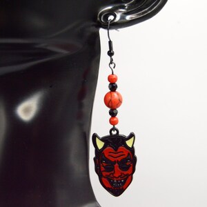 May include: Red devil face dangle earrings with black beads and a black hook.