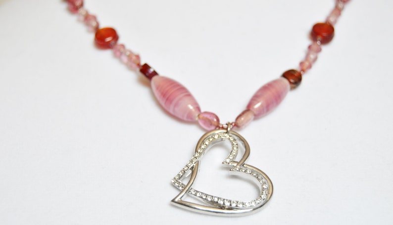 Red and Pink glass handmade beads holding a double heart in silver and crystals.