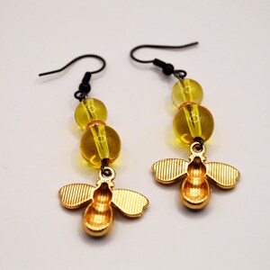 Pu&ograve; includere: Un paio di orecchini a forma di ape color oro con ganci neri. Ogni orecchino presenta tre perline gialle e un ciondolo a forma di ape dettagliato. Gli orecchini sono progettati per ciondolare.