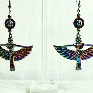 May include: A pair of iridescent earrings featuring a winged goddess design with a circular bead and a dangling bead at the top.