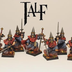 Peut inclure: Figurines miniatures de guerriers fantastiques, chacun avec un chapeau conique, une cape rouge et des robes bleues. Ils sont armés d'épées et se tiennent sur des socles carrés. Le mot "TALF" est affiché au-dessus.