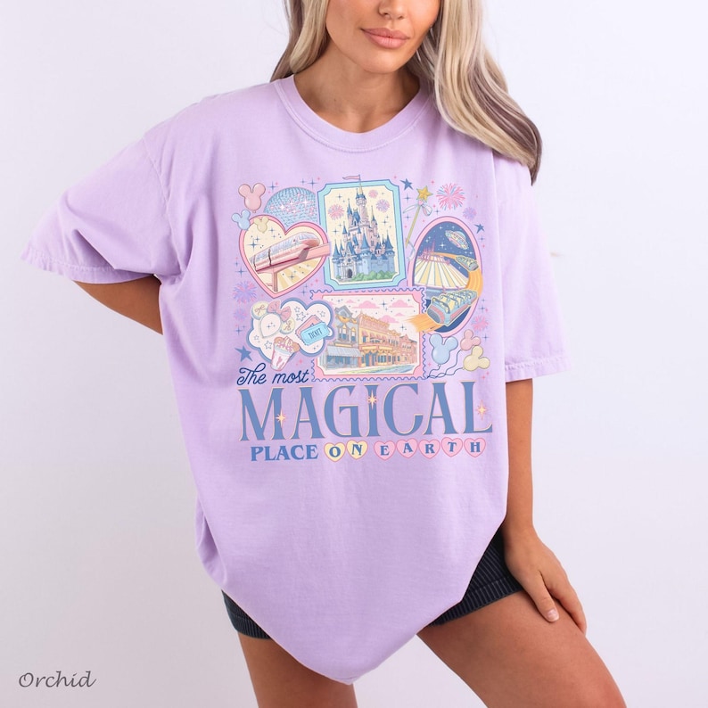 Pu&ograve; includere: Una maglietta lilla chiaro con un design grafico che presenta varie illustrazioni, tra cui un castello, un treno e altre immagini a tema. Il testo "The most MAGICAL PLACE ON EARTH" &egrave; visualizzato in blu e bianco. La parola "Orchid" &egrave; stampata in basso a sinistra.