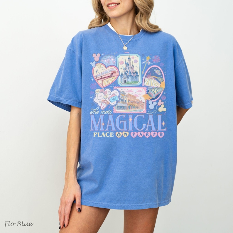 Pu&ograve; includere: Una maglietta blu con un design grafico con varie illustrazioni e la scritta "The most MAGICAL PLACE ON EARTH". Il design include immagini di un castello, un treno e altri elementi del parco a tema.