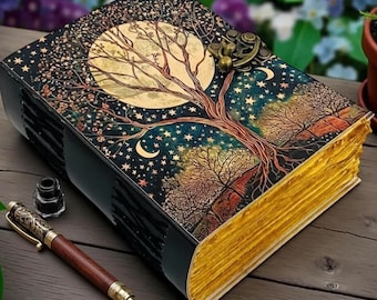 Puede incluir: Un diario decorativo con un diseño celestial que presenta un árbol, una luna y estrellas. El diario tiene una cubierta negra con bordes dorados y un cierre de metal. Una pluma de madera y un tintero se colocan junto al diario sobre una superficie de madera.