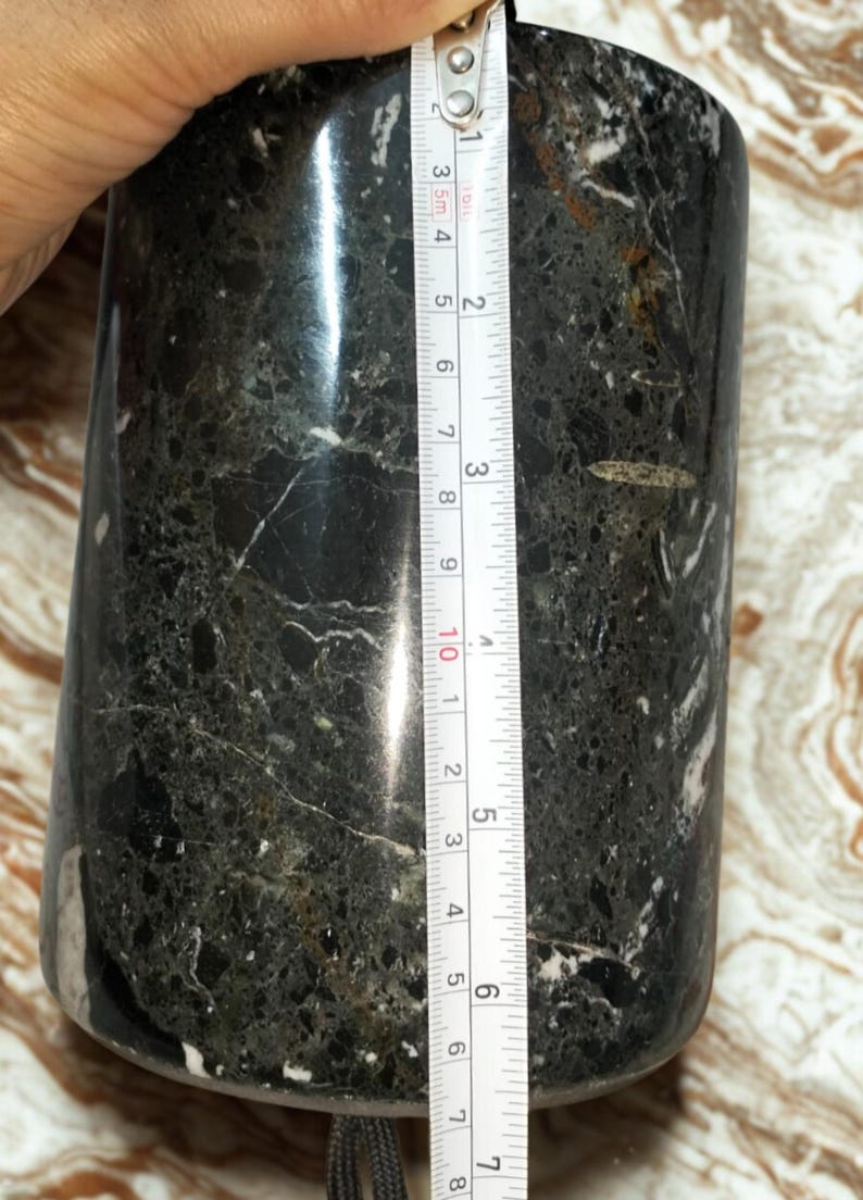 May include: A cylindrical, dark green and black marble container with white veining. The container is approximately 4 inches tall. A measuring tape is placed next to the container.