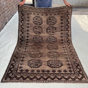 May include: A rectangular, brown rug with a repeating geometric pattern. The rug features a central field with eight octagonal medallions and a detailed border. The color palette includes shades of brown and tan.