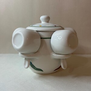 May include: White ceramic tea set with a matching lid and four attached cups. The set features a decorative design of colorful stripes and a green border. The cups are round and have a handle-less design.