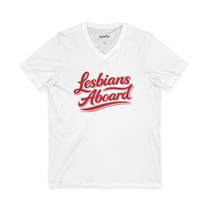 May include: A white short-sleeved V-neck t-shirt featuring the red script text Lesbians Aboard printed across the chest. The interior neck label displays the brand name StimChic in black text on a white background.