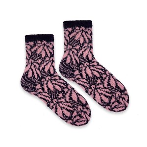 Peut inclure: Une paire de chaussettes tricotées avec un motif de feuilles rose et bleu marine. Les chaussettes ont des poignets et des talons bleu marine. Les chaussettes sont faites d'une matière douce et texturée, conçue pour le confort et la chaleur.
