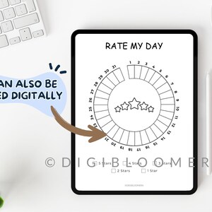 Op de afbeelding: Een digitale planner op een tablet met de tekst "RATE MY DAY". De planner heeft een cirkelvormig beoordelingssysteem met sterren en de nummers 1-31. De tekst "CAN ALSO BE USED DIGITALLY" is ook aanwezig.