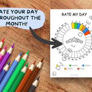 Op de afbeelding: Een witte "Rate My Day" grafiek met een cirkelvormig ontwerp, met een sterrenbeoordelingssysteem en de tekst "RATE MY DAY" en "RATE YOUR DAY THROUGHOUT THE MONTH!". Gekleurde potloden in verschillende kleuren zijn gerangschikt op een houten oppervlak.