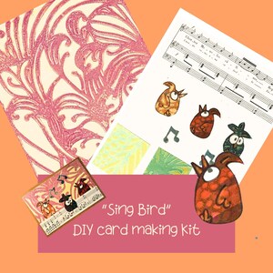 May include: A DIY card making kit with the text "Sing Bird". The kit includes a card with illustrations of singing birds, sheet music, and patterned paper in pink and cream. The kit also includes a card with illustrations of singing birds, sheet music, and patterned paper.
