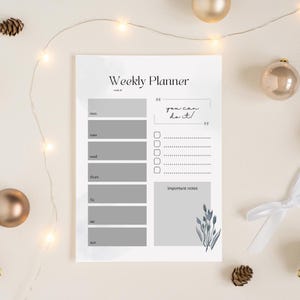 Op de afbeelding: Een weekplanner met een minimalistisch ontwerp. De planner heeft secties voor elke dag van de week, een takenlijst en ruimte voor belangrijke notities. De tekst "Weekly Planner" en "you can do it!" zijn zichtbaar.