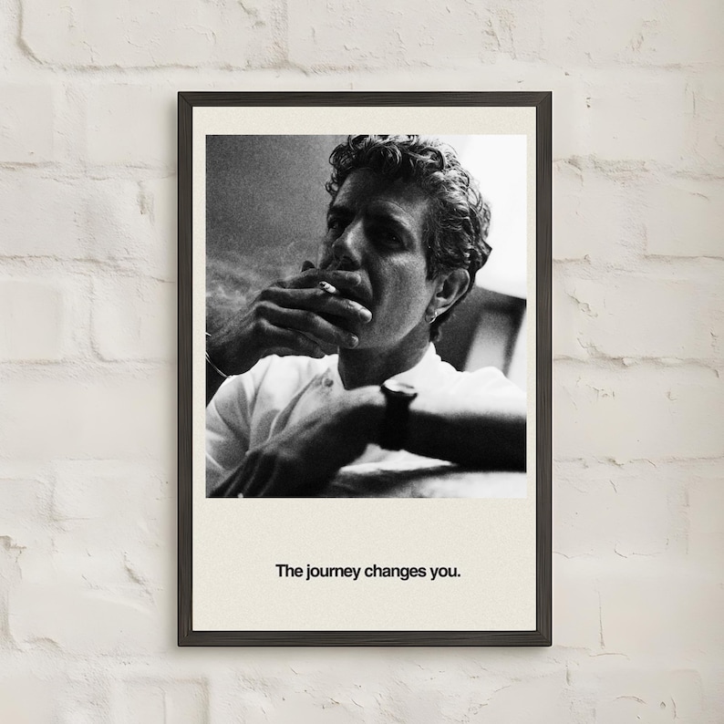 May include: Black and white framed print featuring a portrait of a person smoking a cigarette. The person is wearing a white shirt and has curly hair. The text "The journey changes you." is printed at the bottom of the print.