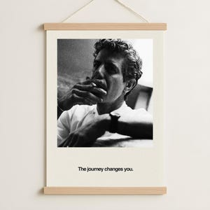 May include: Black and white photograph print of a person smoking a cigarette. The person is wearing a white shirt and has curly hair. The print is mounted on a wooden frame with the text "The journey changes you."