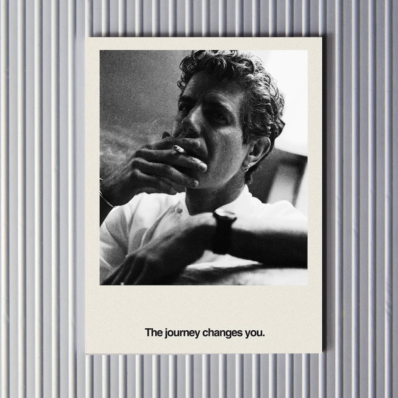 May include: Black and white photograph of a man smoking a cigarette, with the text "The journey changes you." The image is a portrait, with the man's face and upper body visible. The photograph is on a cream-colored background.