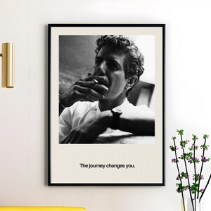 May include: Black and white framed print featuring a man smoking a cigarette. The man is wearing a white shirt and a watch. The print includes the text "The journey changes you."