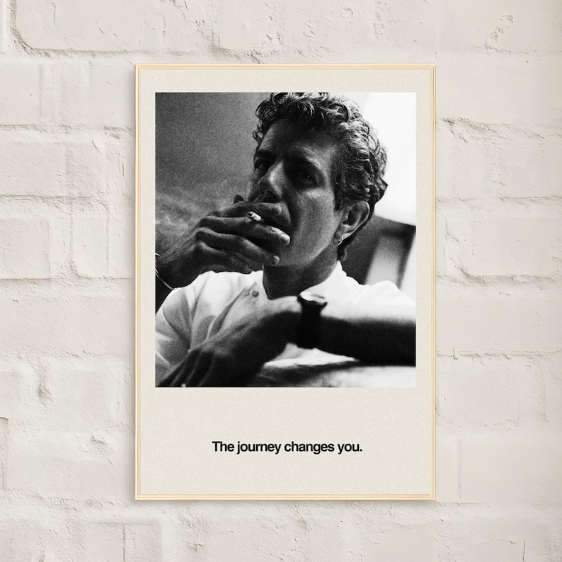 May include: Black and white framed print featuring a man smoking a cigarette. The man is wearing a white shirt and has curly hair. The print has the text "The journey changes you."