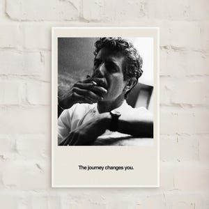 May include: Black and white framed print featuring a man smoking a cigarette. The man is wearing a white shirt and a watch. The text "The journey changes you" is printed at the bottom of the print.