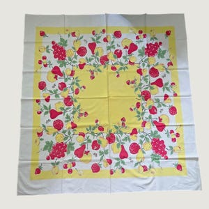 May include: A square tablecloth featuring a white centre and a wide yellow border. The fabric is decorated with a repeating pattern of red strawberries, red grapes, and yellow pears, all connected by green leafy vines and small stems.