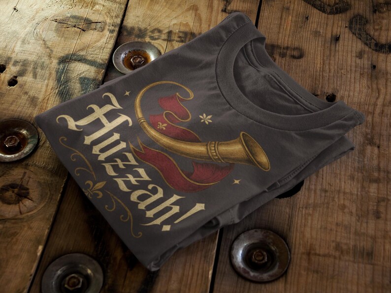 Vintage style Huzzah t-shirt with trumpet and banner medieval design folded on rustic wood.