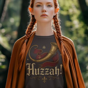 Medieval fantasy Huzzah shirt worn by elf-inspired woman at renaissance fair woods cosplay.