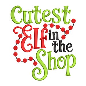 May include: A whimsical design with the text "Cutest Elf in the Shop" in green, red, and black. The word "Elf" is in a large, ornate red font, and the design includes a string of red beads.