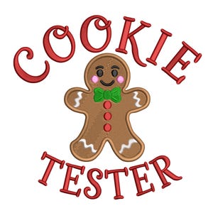 May include: A brown gingerbread man with a green bow tie and red buttons is centered on a white background. The words "COOKIE TESTER" are embroidered in red above and below the gingerbread man.
