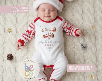 May include: A baby wearing a white and red Christmas-themed onesie and Santa hat. The onesie features a festive design with reindeer, Santa, and the text "My First Christmas RORY 2025". The words "100% Cotton Clothing" are also visible.