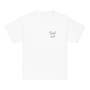 Könnte beinhalten: Ein weißes T-Shirt mit dem Wort "Smile" in handschriftlicher Schrift und einem kleinen lächelnden Gesicht, das in schwarzer Tinte gedruckt ist. Das Design befindet sich auf der oberen Brust. Das T-Shirt hat kurze Ärmel und einen Rundhalsausschnitt.
