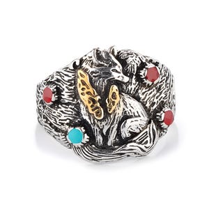 May include: A silver-toned ring featuring a detailed fox design with gold accents and red and turquoise gemstones. The ring has an intricate, textured surface and a bold, artistic style.