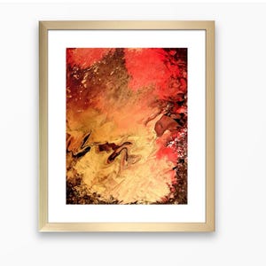 May include: Abstract art print in a gold frame. The artwork features a blend of red, orange, brown, and gold hues, creating a dynamic and textured visual effect. The frame is a simple, gold-colored rectangle.