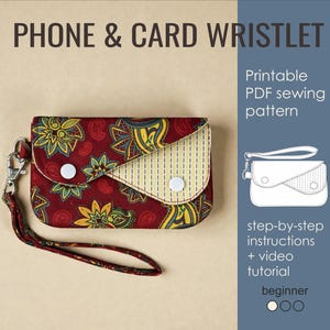 Può includere: Un portacarte e telefono bordeaux con un motivo paisley floreale e una patta a righe gialle e bianche. Il cinturino ha una chiusura argentata e un cinturino da polso bordeaux abbinato. Il testo "PHONE & CARD WRISTLET" è in alto.