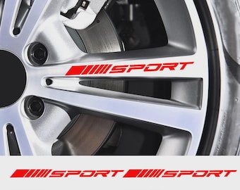 May include: Close-up of a silver car wheel with a red "SPORT" decal. The decal is repeated at the bottom of the image. The wheel has a brake disc and caliper visible.
