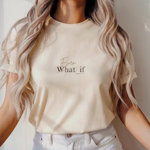 Könnte beinhalten: Cremefarbenes T-Shirt mit dem Text "Even What if" in einer stilvollen Schriftart. Der Bibelvers Jesaja 41,10 ist ebenfalls enthalten. Das kurzärmelige Shirt hat eine neutrale Farbe und eignet sich für Freizeitkleidung.