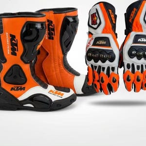 Könnte beinhalten: Motorradstiefel und -handschuhe in Orange und Schwarz. Die Stiefel und Handschuhe zeigen das KTM Racing Team Logo und das Red Bull Branding. Die Stiefel sind hauptsächlich orange mit schwarzen Akzenten und weißen Details. Die Handschuhe sind weiß, orange und schwarz.