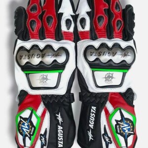 Peut inclure: Paire de gants de moto noirs, blancs et rouges. Les gants présentent le logo "MV AGUSTA" et un motif en forme d'étoile avec des accents verts et bleus. Les gants ont une protection des jointures.