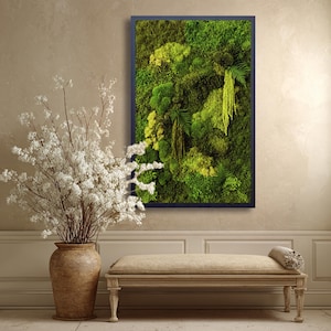 May include: A framed vertical wall art piece featuring a vibrant display of preserved moss and ferns in shades of green and yellow. The artwork is encased in a dark blue frame, creating a natural, textured aesthetic. The artwork is displayed above a bench.
