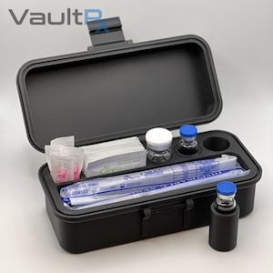 May include: Black medical storage case with an open lid, containing vials, syringes, and other medical supplies. The case has a latch and the text "VaultRx" is visible on the top left.