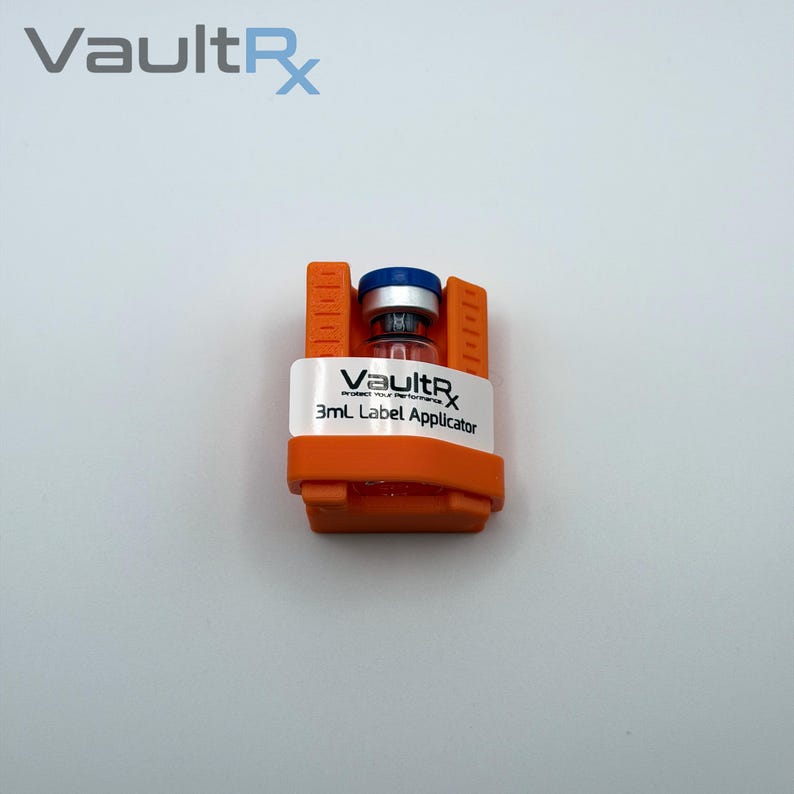 May include: An orange 3mL label applicator with a clear vial and a blue cap. The applicator has the text "VaultRx" and "3mL Label Applicator" printed on a white label.
