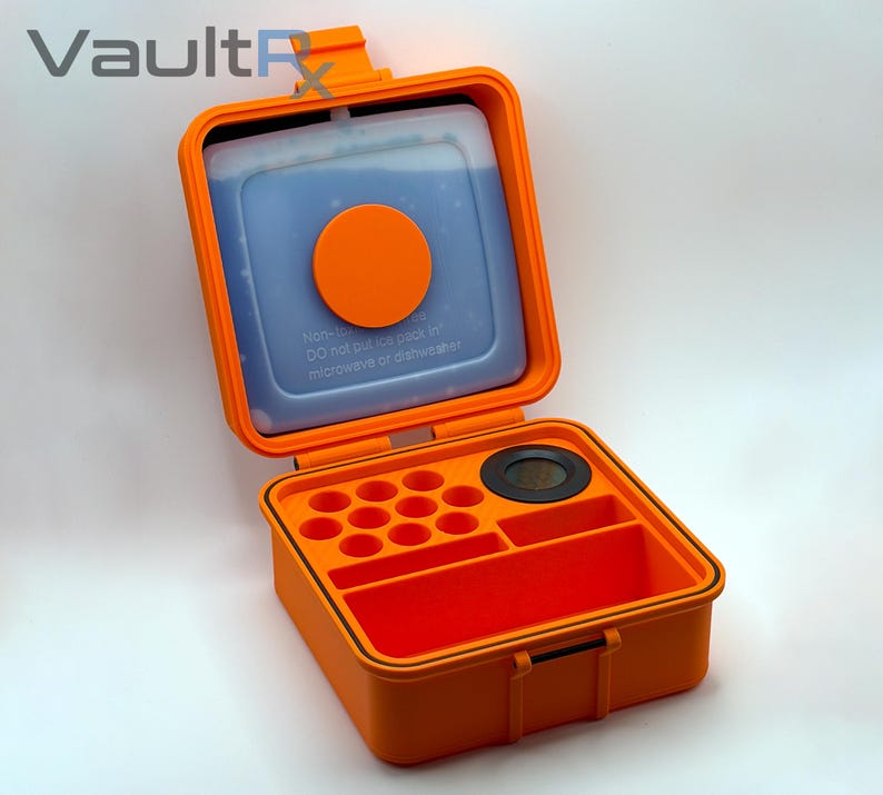 May include: An open orange storage container with a blue ice pack and an orange circle. The container has compartments for organization. The text "VaultRx" is in the upper left corner. The container is on a white background.