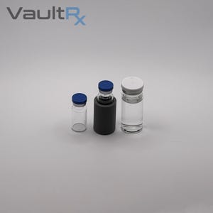 May include: Three glass vials with blue and white caps. One vial is in a black holder. The vials are empty and clear. The text "VaultRx" is in the upper left corner.